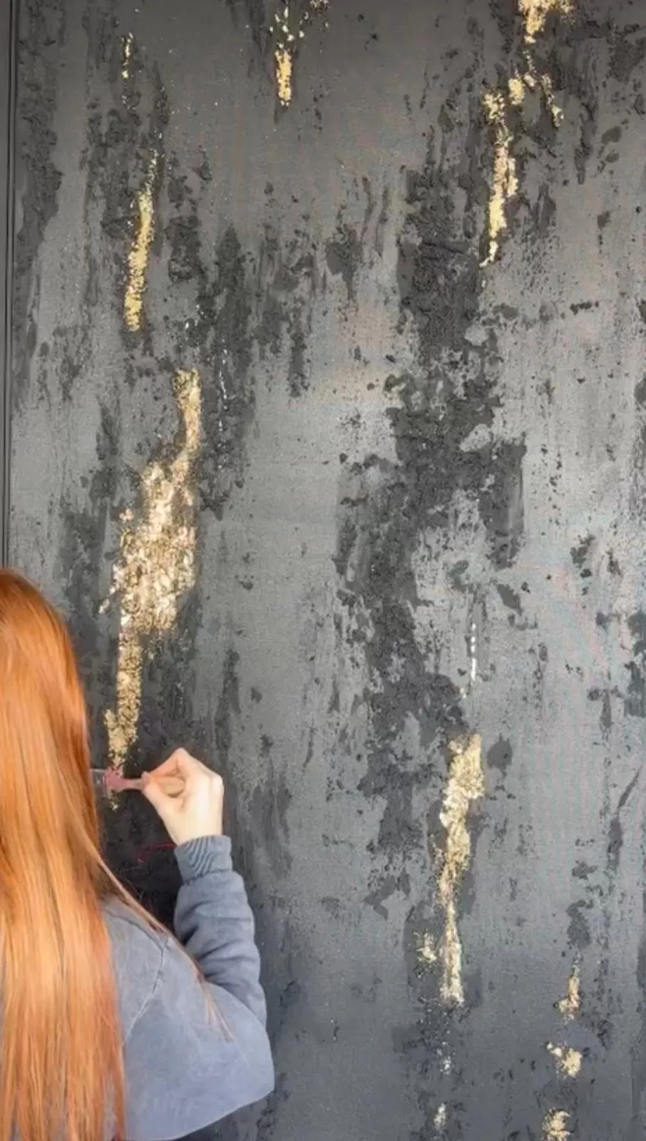 Sofía aplicando pan de oro sobre una obra negra con textura